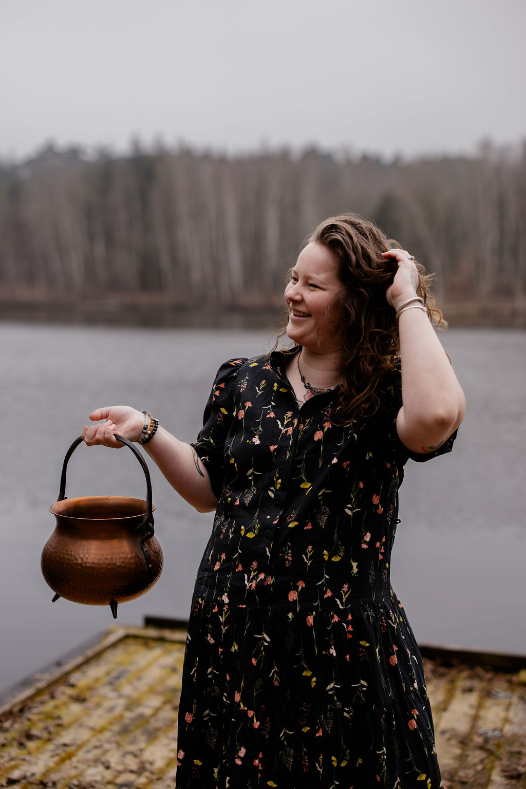 Cécile Kerremans souriante au bord d'un lac, chaudron en cuivre à la main